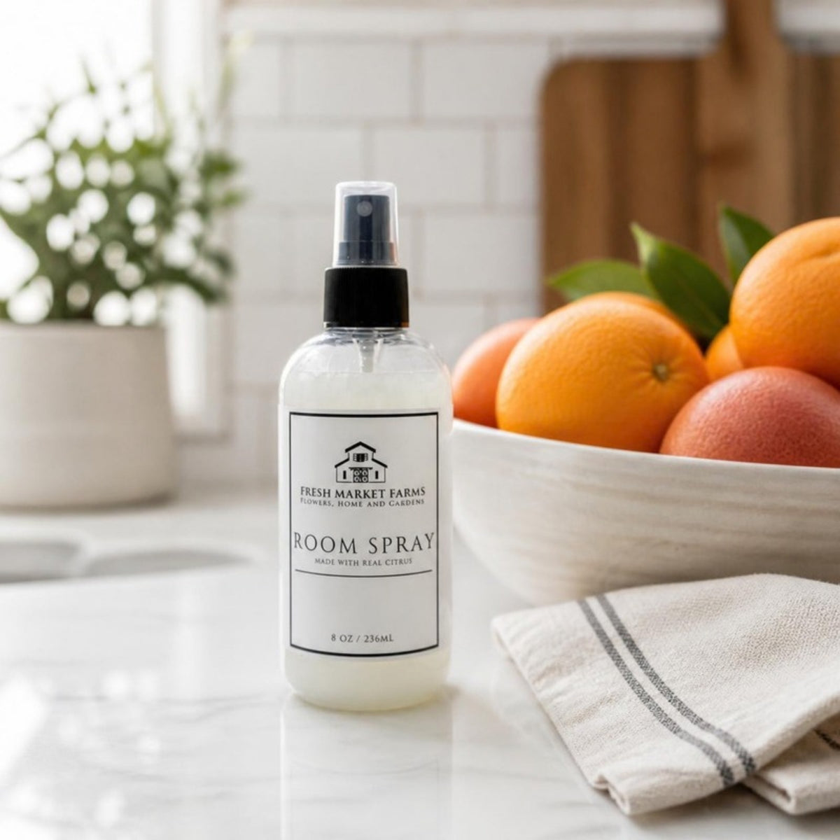 Citrus Room Spray on a kitchen counter beside a bowl of citrus