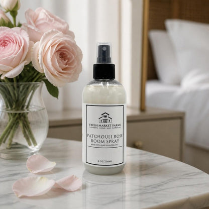 Rose & Patchouli Room Spray beside pink garden roses